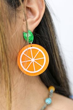 Our Fresh Citrus Earrings feature an orange citrus design that is sure to brighten up any look. The lightweight construction and high quality resin make these earrings comfortable and resilient. Step out in style with these beautiful and unique earrings. Details:- Sparkling Orange Slice Drop Earrings- Stud Post BackingDimensions:- Length Approx. 2.5"- Width Approx. 1.75" Orange Dangle Resin Earrings, Orange Resin Dangle Earrings, Summer Orange Jewelry With Fruit Design, Orange Fruit Design Earrings As Gift, Trendy Orange Plastic Jewelry, Orange Earrings For Summer Gifting, Trendy Orange Drop Earrings, Trendy Orange Earrings For Summer, Orange Round Earrings For Summer