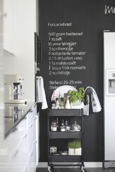 a black and white kitchen with chalkboard on the wall