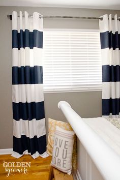 a bed room with a neatly made bed and striped curtains on the window sill