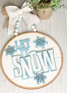 a wooden sign that says let the snow on it next to a potted plant