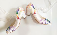 two pairs of white shoes decorated with multicolored beads