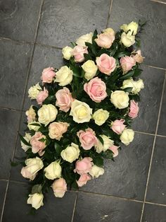 a bunch of flowers that are sitting on a tile floor in front of a wall