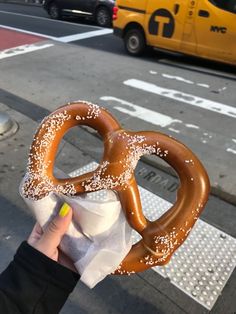 a person holding up a pretzel on the street