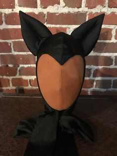 a black cat mask on top of a wooden table next to a brick wall and floor