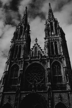 black and white photograph of the front of a gothic church with clouds in the background