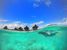 a man swimming in the ocean next to some huts