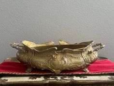 two metal bowls sitting on top of a red cloth next to a silver tray with an ornate design