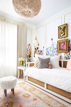 a white bed sitting in a bedroom next to a window filled with curtains and pillows