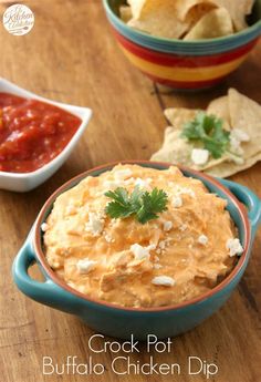 two bowls filled with dip and chips on top of a wooden table next to salsa