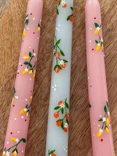 three pink and white candles sitting on top of a wooden table next to each other