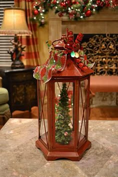 a christmas lantern sitting on top of a table in front of a fire place filled with decorations