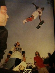 a man flying through the air while riding a skateboard in front of other people