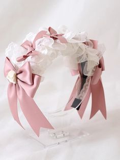 a pink and white flowered headband on a clear display stand with ribbon around it