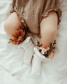 a baby's feet wearing white socks with flowers on them