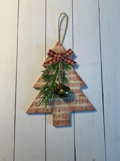 a wooden christmas tree ornament hanging from a string on a white wood wall