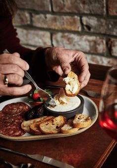 a person is cutting bread with a knife and fork on a plate next to other food