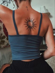 the back of a woman's shoulder with a cross and sun tattoo on it