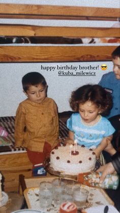 two children are sitting in front of a birthday cake