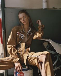 a woman sitting on the back of a truck next to a can of soda wearing an air force pilot's uniform