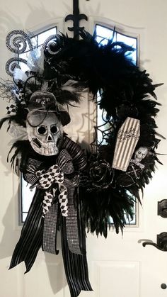 a wreath decorated with black feathers and a skeleton wearing a hat is hanging on the front door