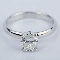 a white gold ring with a round cut diamond in the center, on a plain surface