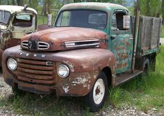 two old trucks parked next to each other in the grass