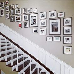 a staircase with pictures on the wall and framed photos on the wall above it, along with a banister