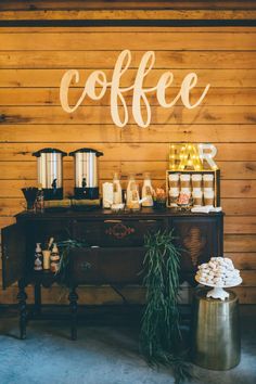 a table with coffee and pastries on it in front of a wooden wall that says coffee