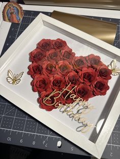 a white frame with red roses in it and the words love is spelled on it