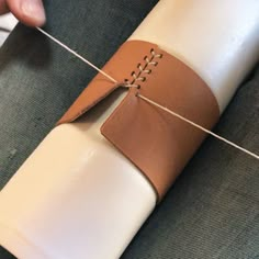 someone is wrapping up a roll of white paper with brown stitching on the end