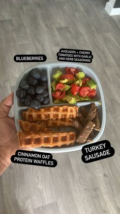 a person holding a plate with different types of food on it, including waffles and grapes