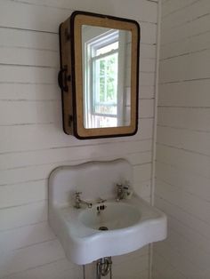 a white sink sitting under a mirror in a bathroom next to a wall mounted faucet