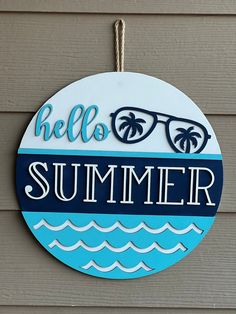 a sign that says hello summer hanging from the side of a building with sunglasses on it