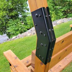 a wooden bench with black metal brackets on it's sides and grass in the background