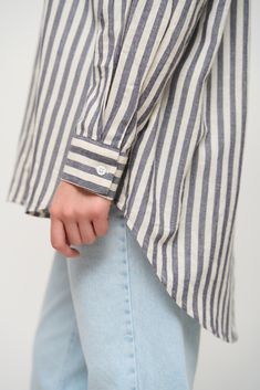 This loose-fitting striped shirt is a practical and stylish piece of clothing. Made of 100% cotton, it provides a light, comfortable, and confident feel all day long. The model is versatile, serving as a stand-alone piece or as part of a layered look. The vertical lines create a lengthening effect on the silhouette, resulting in a slimmer appearance. This shirt pairs well with both jeans and classic trousers. Striped Cotton Shirt For Work, Cotton Button-up Tops With Horizontal Stripes, Long Sleeve Cotton Shirt With Horizontal Stripes, Casual Striped Blouse With Shirttail Hem, Classic Striped Blouse With Relaxed Fit, Pinstripe Cotton Shirt With Striped Collar, Cotton Button-up Tops With Vertical Stripes, Casual Pinstripe Tops For Daywear, Everyday Long Sleeve Top With Striped Collar