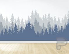 an empty room with wood floors and trees painted on the wall in front of it