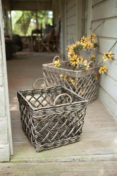 two wicker baskets sitting on the front step of a house with flowers in them