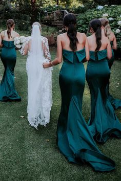 bridesmaids in green dresses walking down the grass with their backs to each other