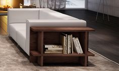 a white couch sitting next to a book shelf on top of a carpeted floor