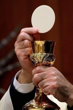 a man holding a glass with a white disc in it's hand while wearing a suit and tie