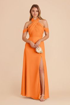 a woman in an orange dress posing with her legs crossed and wearing a high slited skirt