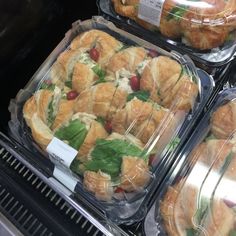 several trays of sandwiches sitting on top of a shelf in a store display case