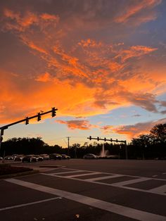 an intersection with traffic lights and cars at sunset