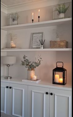 some white shelves with candles and flowers on them