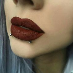 a woman with red lipstick and piercings on her nose