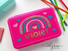 there is a pink lunch box with writing on it next to colored pencils and markers