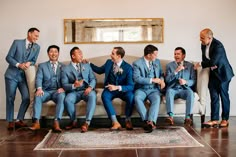 a group of men sitting on top of a couch next to each other in suits