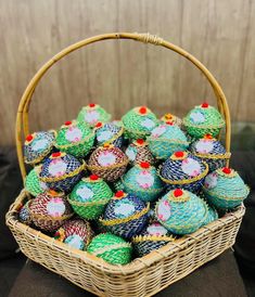 a basket filled with lots of colorfully decorated cupcakes on top of a table