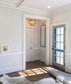 the sun shines through the windows in this white room with wood flooring and rugs on the floor