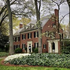 a large brick house surrounded by trees and flowers